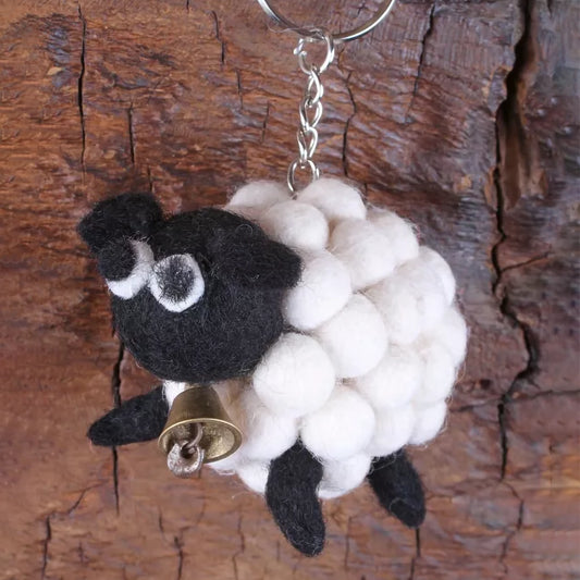 A felted pompom keyring shaped like a white sheep with a brass bell detail