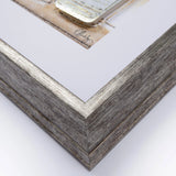 Close-up detail of bottom left corner of grey washed wooden frame with silver foil strip and white matt.