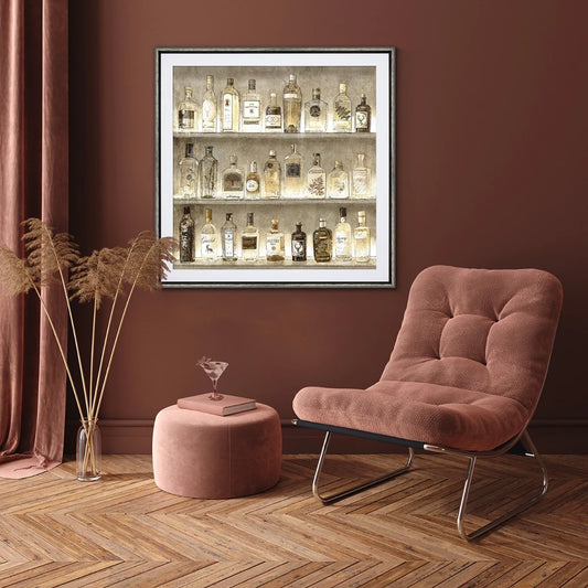 Framed print of liquor bottles with raised paper details and metallic paper in vintage style hanging in dark room.