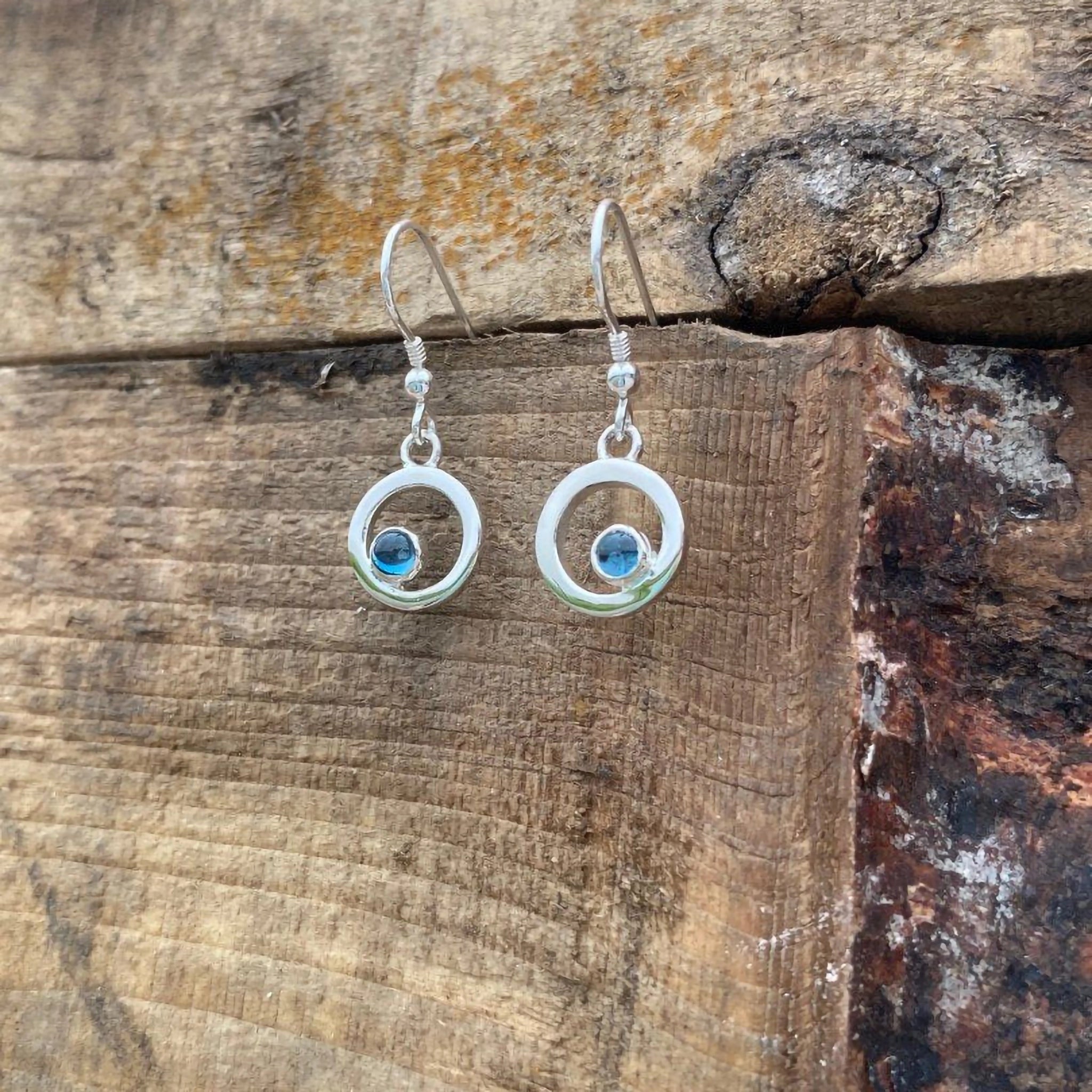 A pair of round silver frame drop earrings with blue topaz stones