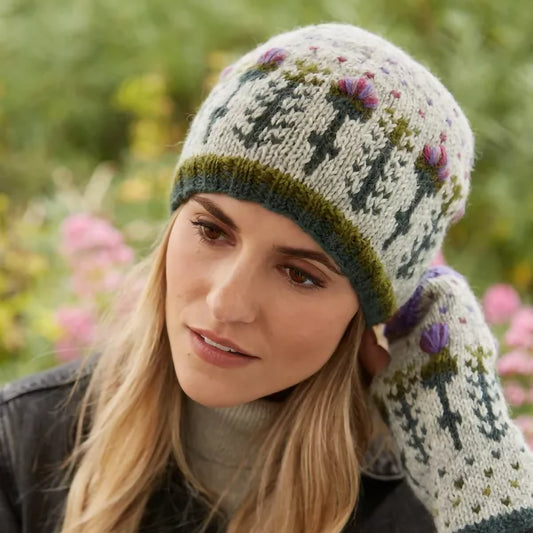Model wearing a knitted grey hat featuring a repeating thistle pattern with hearts