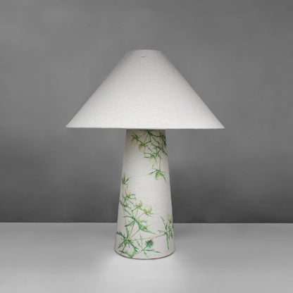 A fabric table lamp with shade and a thistle design on the conical base