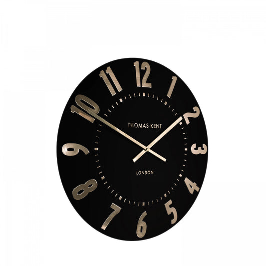 A simple and modern round wall clock in a black colour with gold hands and numbers side view
