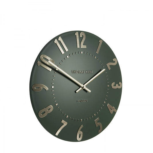 A simple and modern round wall clock in a dark olive green colour with gold hands and numbers side view