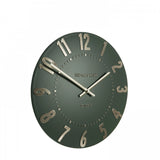 A simple and modern round wall clock in a dark olive green colour with gold hands and numbers side view