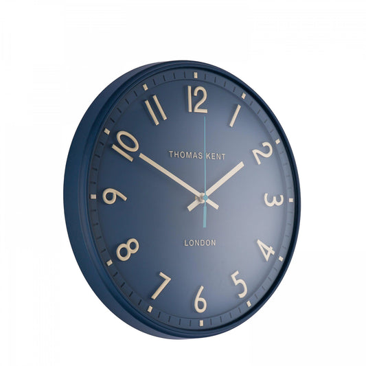 A simple and modern round wall clock in a marine blue colour with gold hands and numbers side view