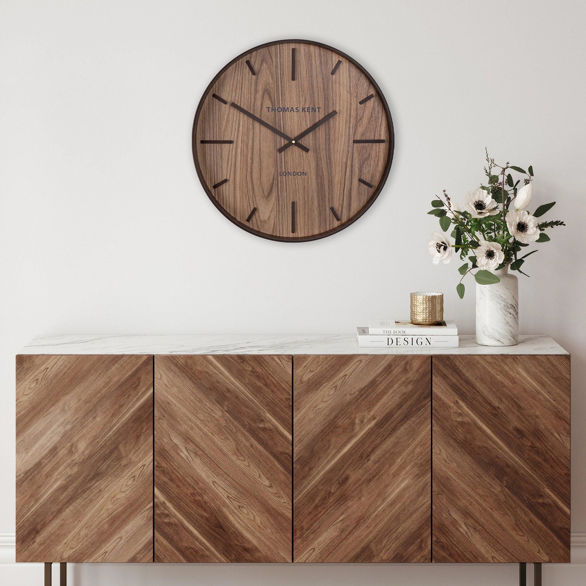 A wall clock with medium wood effect face and simple number markings and hands on wall