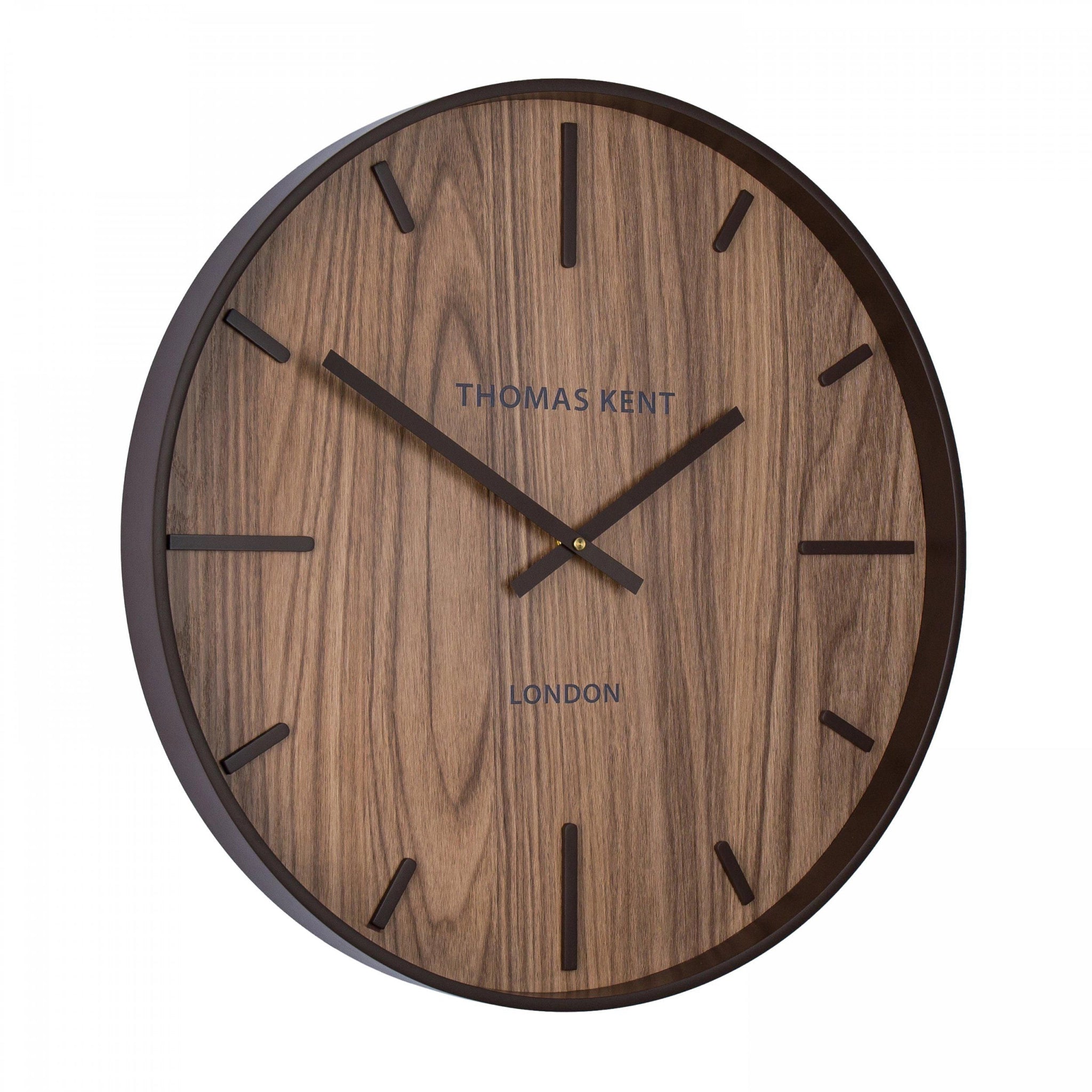 A wall clock with medium wood effect face and simple number markings and hands side view