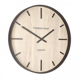 A wall clock with light wood effect face and simple number markings and hands side view