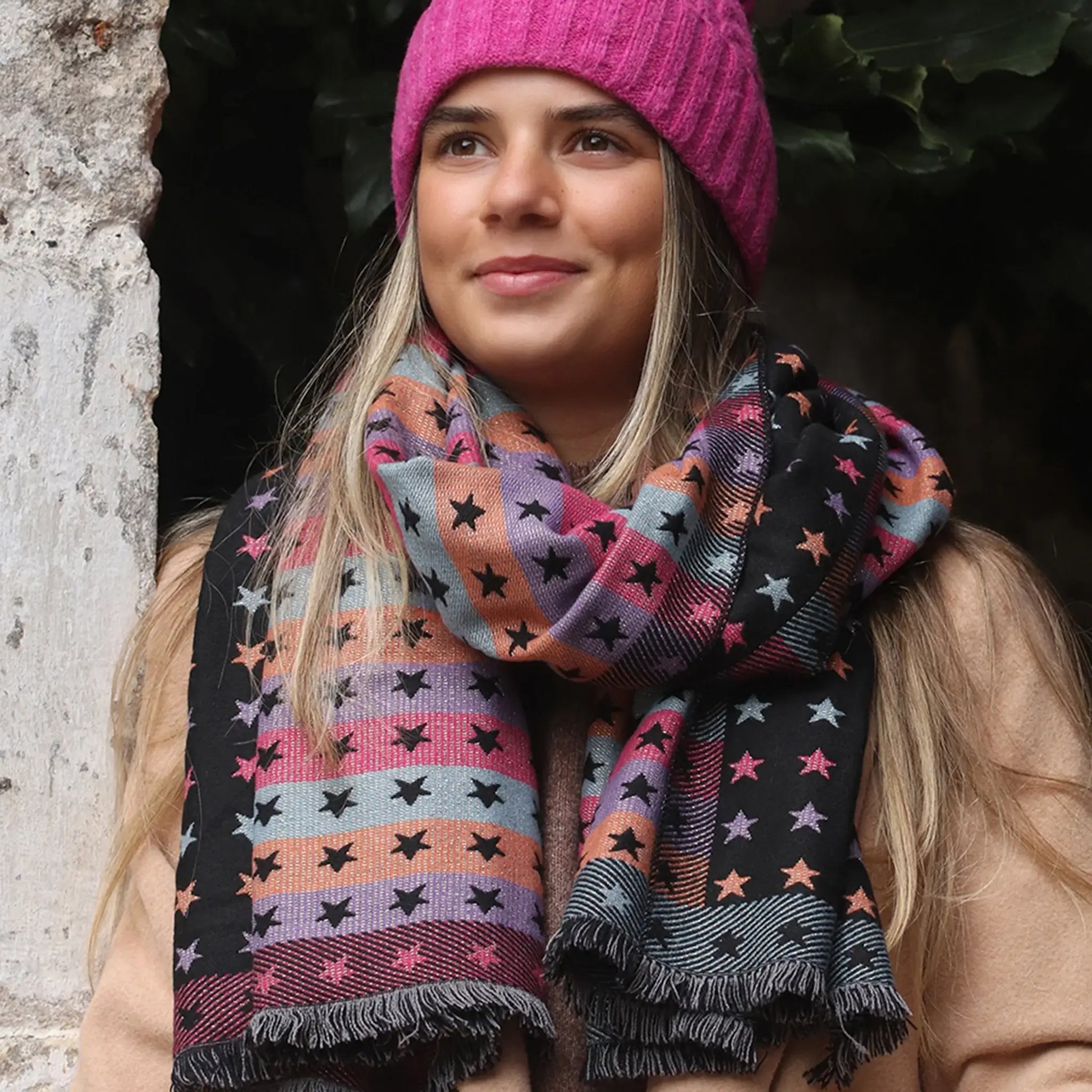 Model wearing reversible black and pastel rainbow stars and stripes scarf
