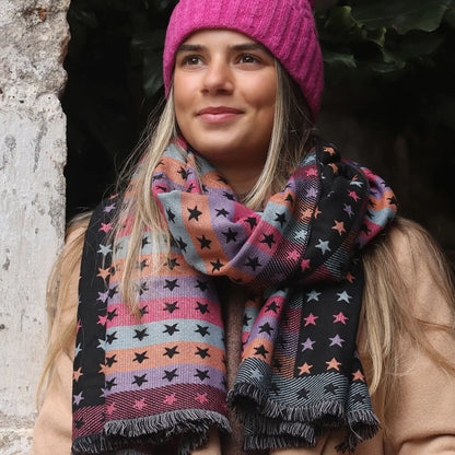 Model wearing reversible black and pastel rainbow stars and stripes scarf