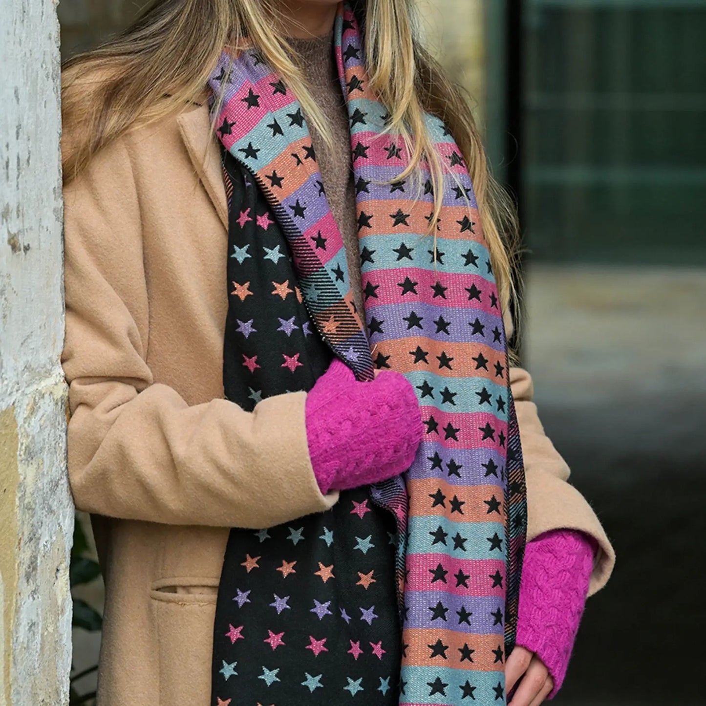Model wearing reversible black and pastel rainbow stars and stripes scarf