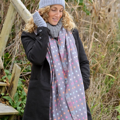 Model wearing reversible grey and pastel rainbow stars and stripes scarf