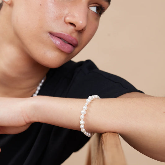 Model wearing a silver toggle clasp bracelet strung with natural shaped white freshwater pearls
