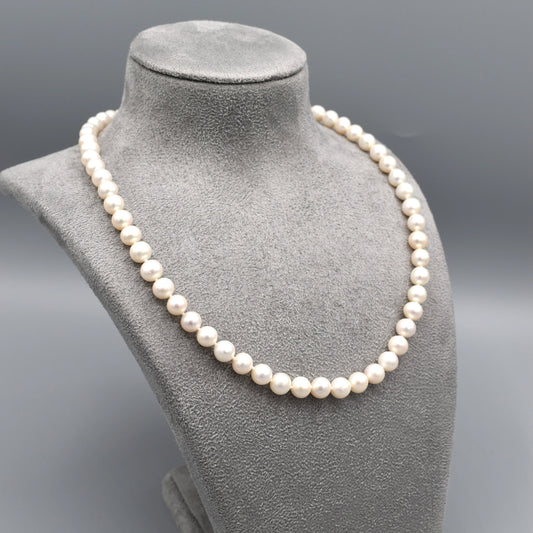 A silver toggle clasp necklace strung with round shaped white freshwater pearls