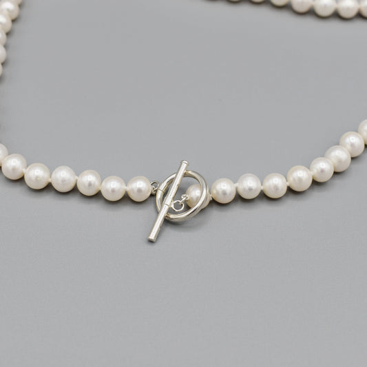 Silver toggle clasp on necklace strung with round shaped white freshwater pearls