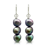 A pair of drop earrings with three stacked natural shaped black pearls and silver hook fittings