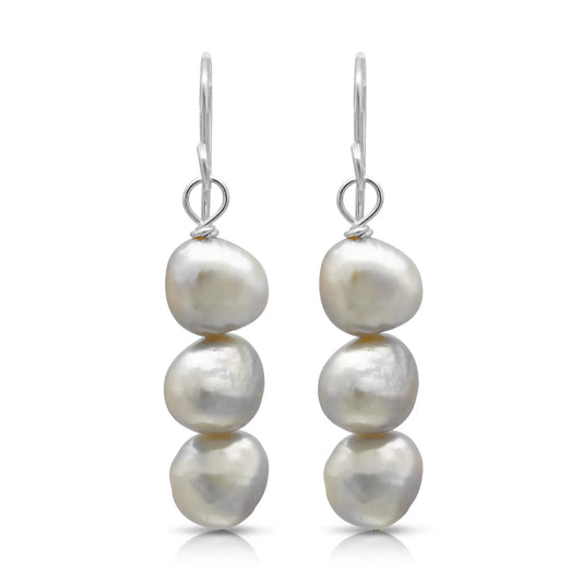 A pair of drop earrings with three stacked natural shaped white pearls and silver hook fittings
