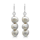 A pair of drop earrings with three stacked natural shaped white pearls and silver hook fittings