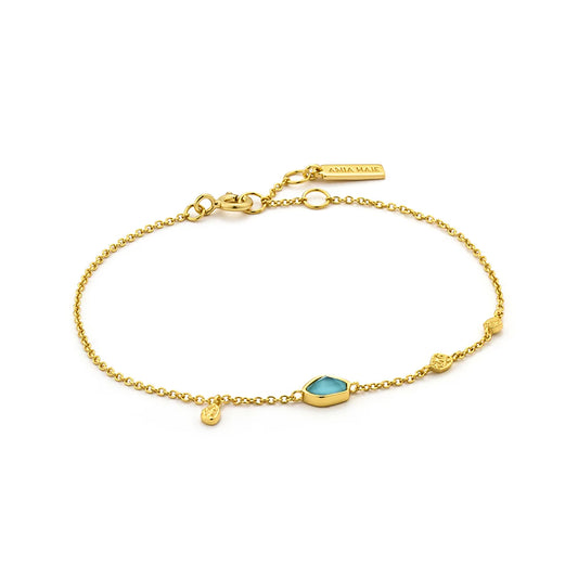 A gold bracelet with irregular turquoise stone and three gold discs