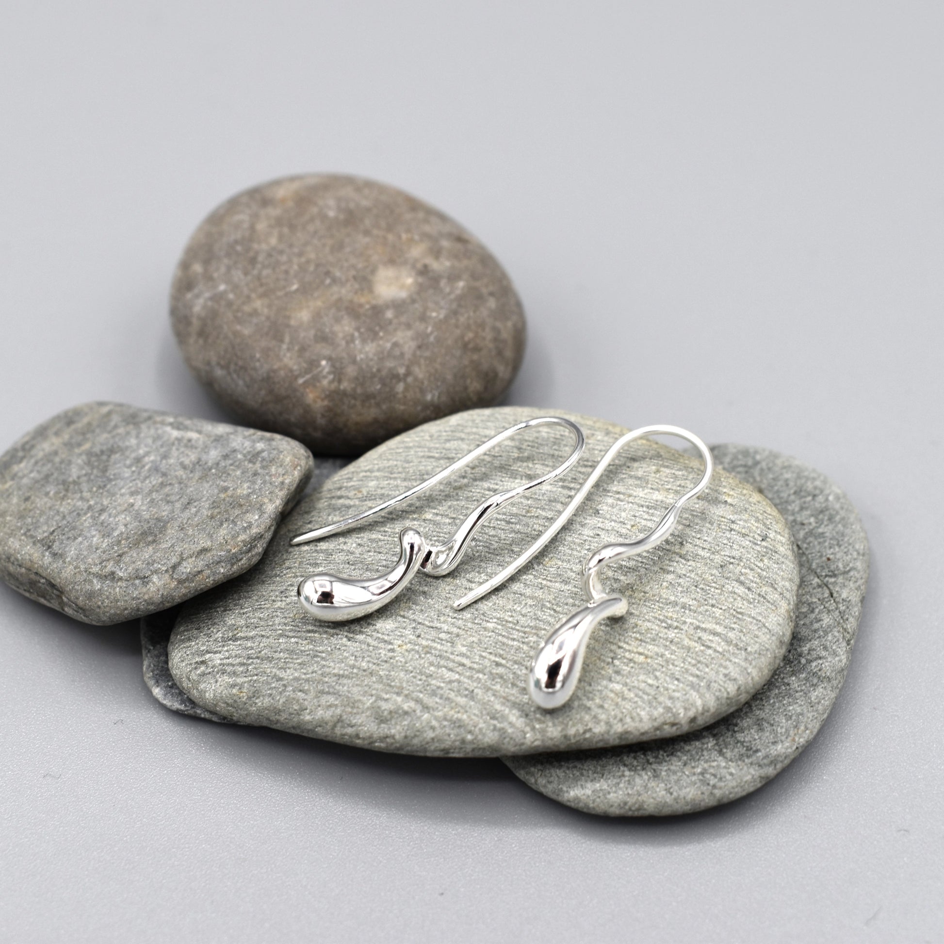 A pair of sterling silver earrings that features a modern design of a long twisted droplet shape