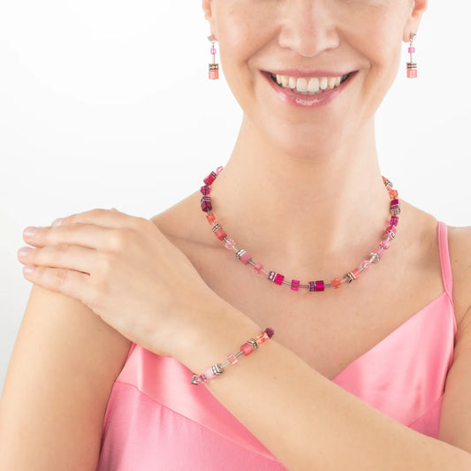 Model wearing a jewellery set with a variety of bright pink cube shaped stones and glass beads