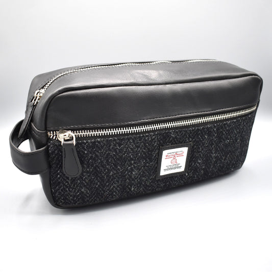 A black faux leather washbag with genuine Harris tweed front in charcoal colour