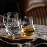 Set of two whisky glasses and a jug on a hexagonal wooden tray posed on fabric 