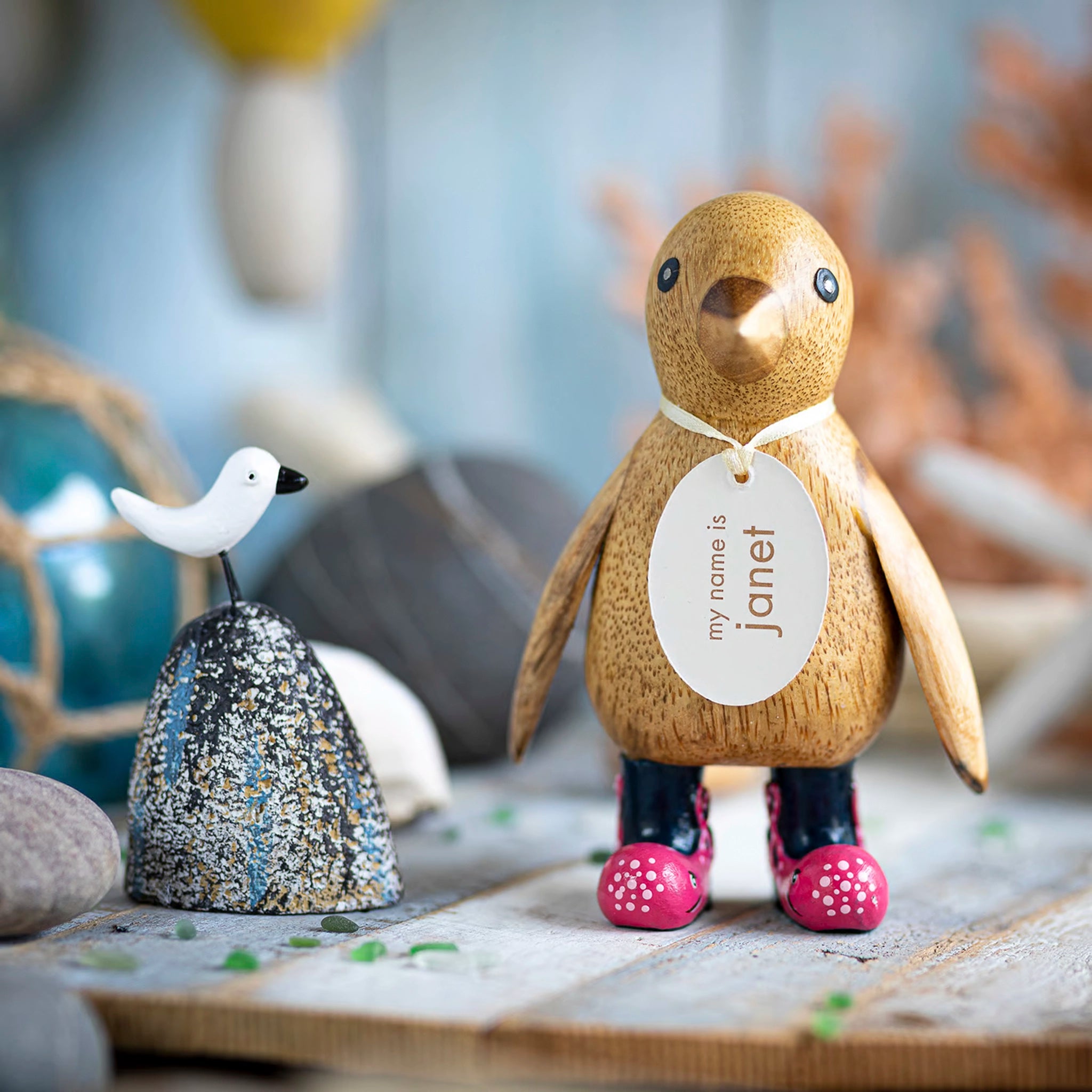 A wooden penguin wearing wellies with pink octopus design lifestyle