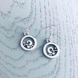 A pair of silver earrings featuring round frames with curled waves in the centre