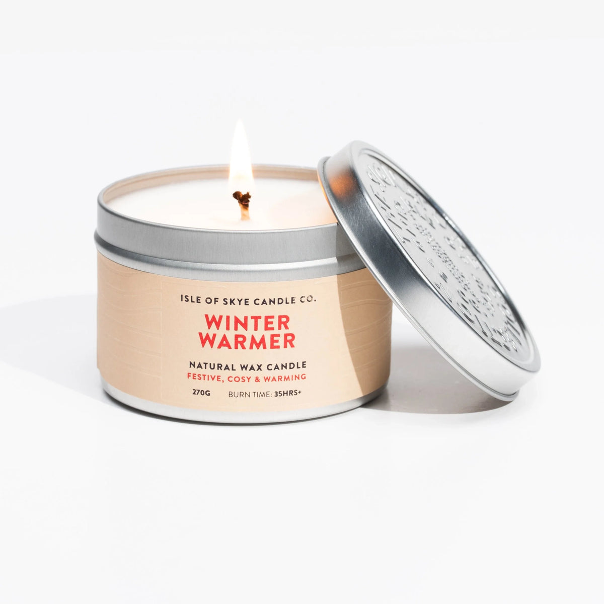 A lit travel tin candle in the scent winter warmer by Isle of Skye Candle Co.