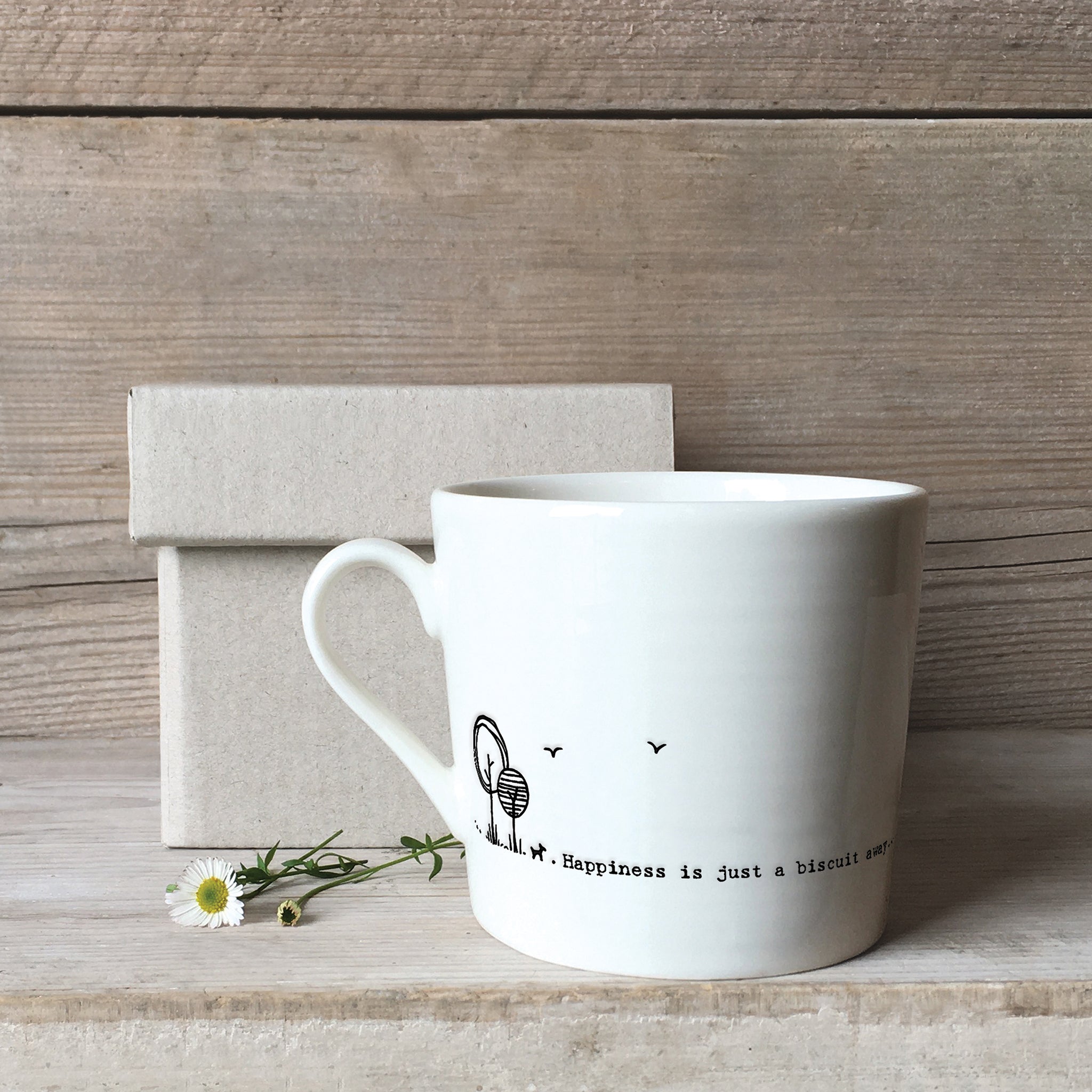 A white ceramic mug with a dog illustration and a quote with a box