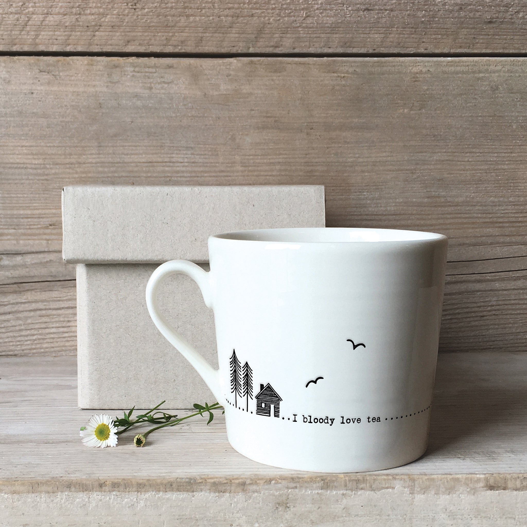 A white ceramic mug with a cabin illustration and a quote with a box