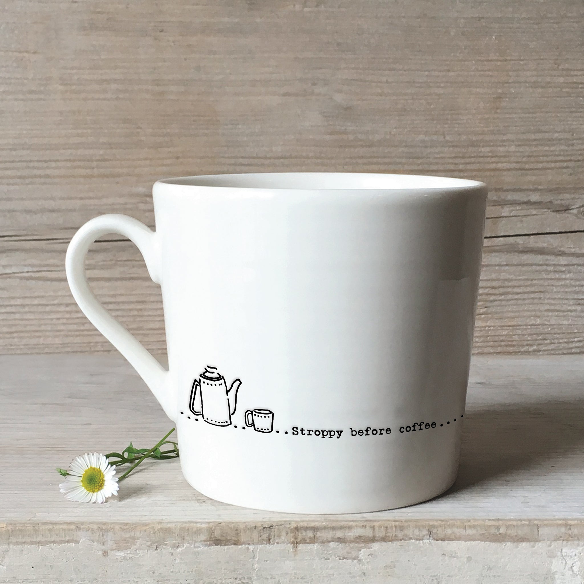 A white ceramic mug with a tea pot illustration and a quote 