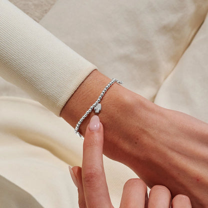 Model wearing a stretch silver beaded bracelet with double heart charm