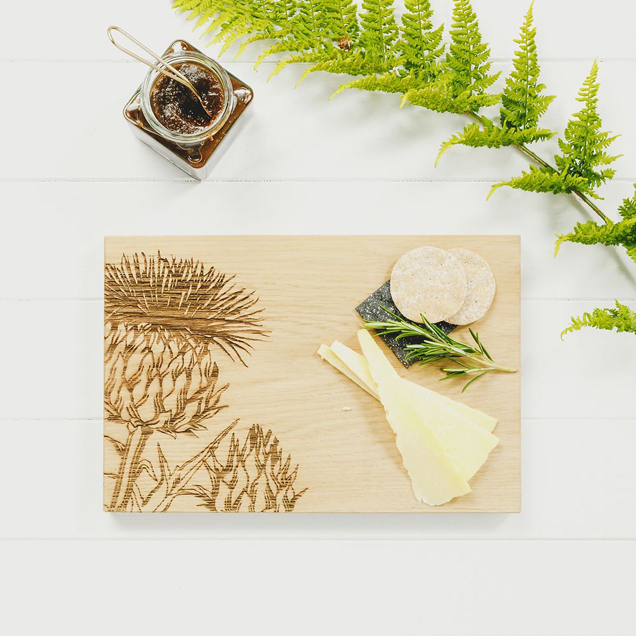 Wooden cutting board with engraved Scottish Thistle staged with cheese and crackers