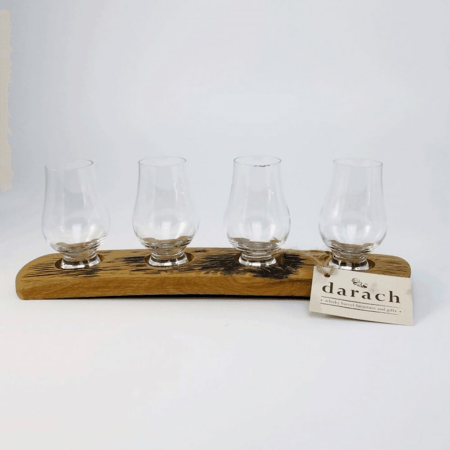 Four nosing whisky glasses on wooden barrel stave