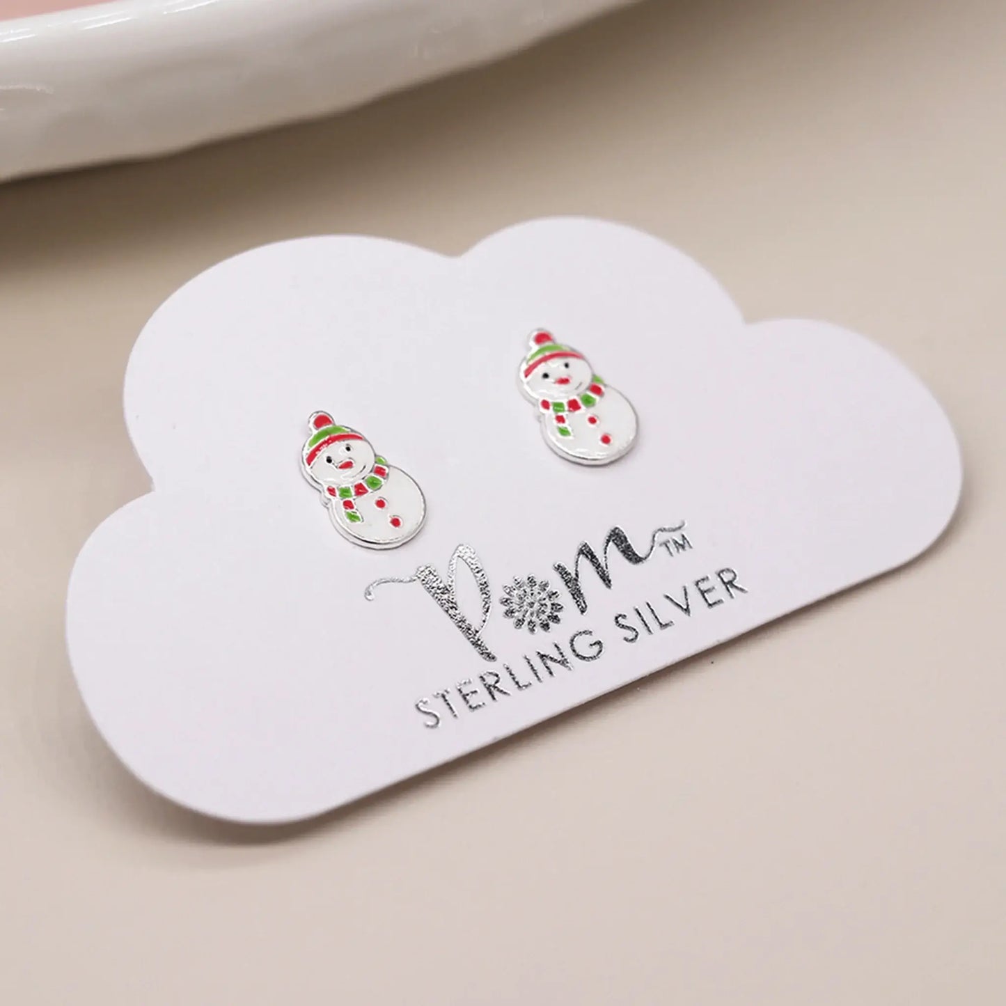 Pair of silver stud earrings shaped like snowmen with enamelled details on packaging card
