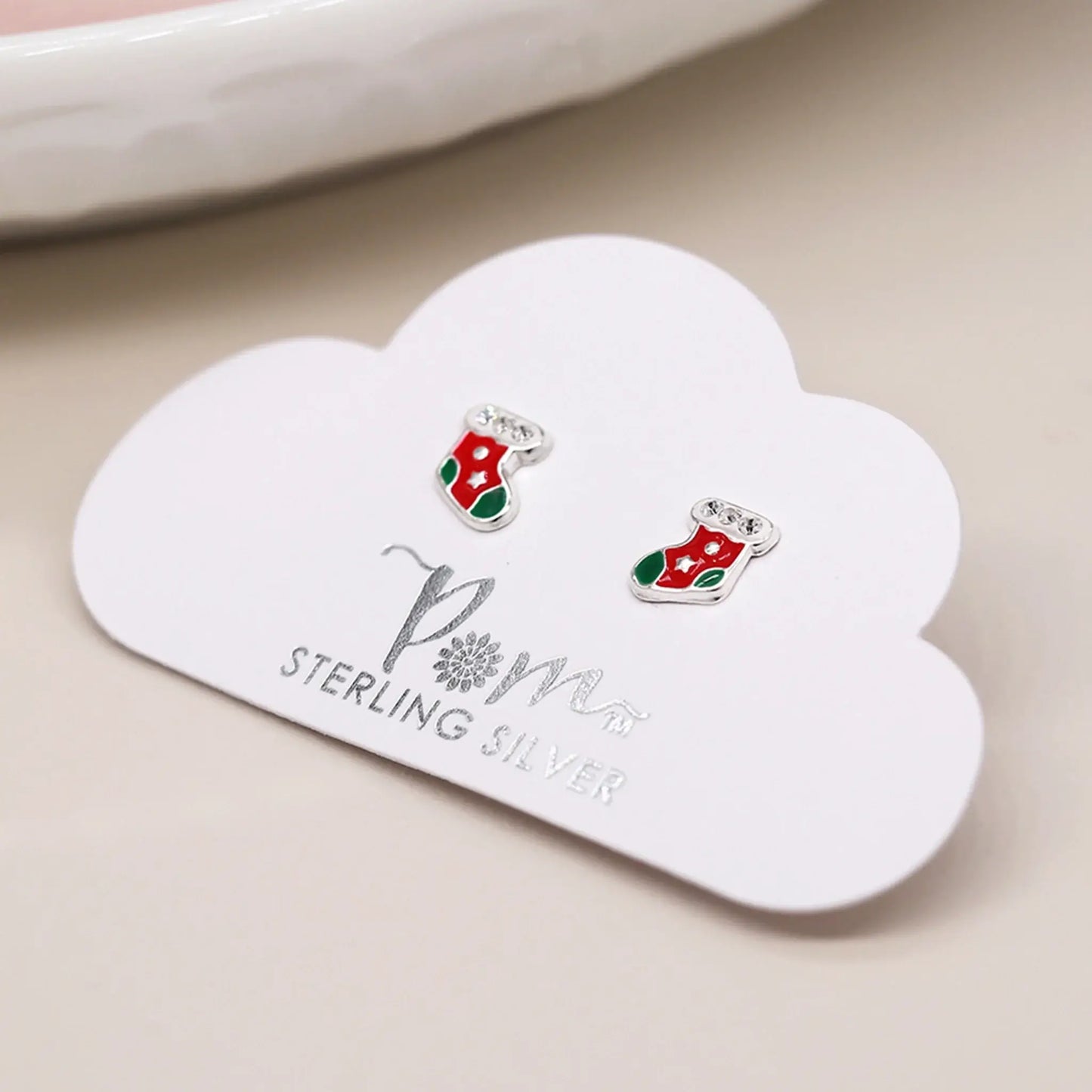 Pair of silver stud earrings shaped like stockings with enamelled details on card