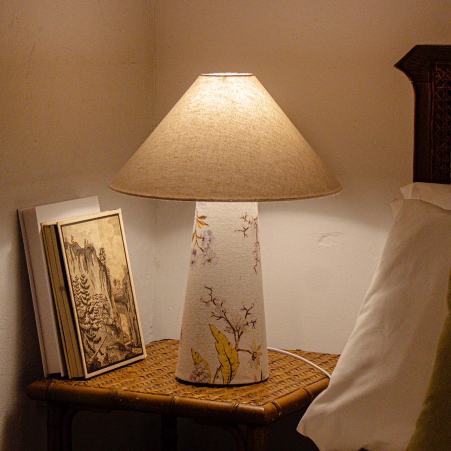 A fabric table lamp with shade and a yellow blossom design on the conical base lifestyle