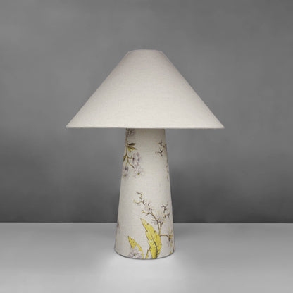 A fabric table lamp with shade and a yellow blossom design on the conical base
