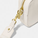 An off-white crossbody bag in a simple box shape with adjustable canvas strap and gold hardware detail