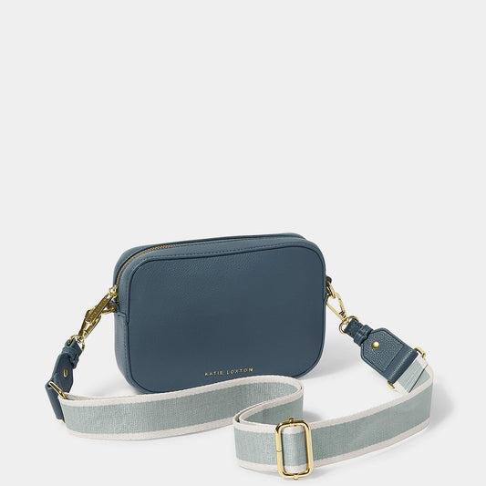 A navy blue crossbody bag in a simple box shape with adjustable canvas strap and gold hardware