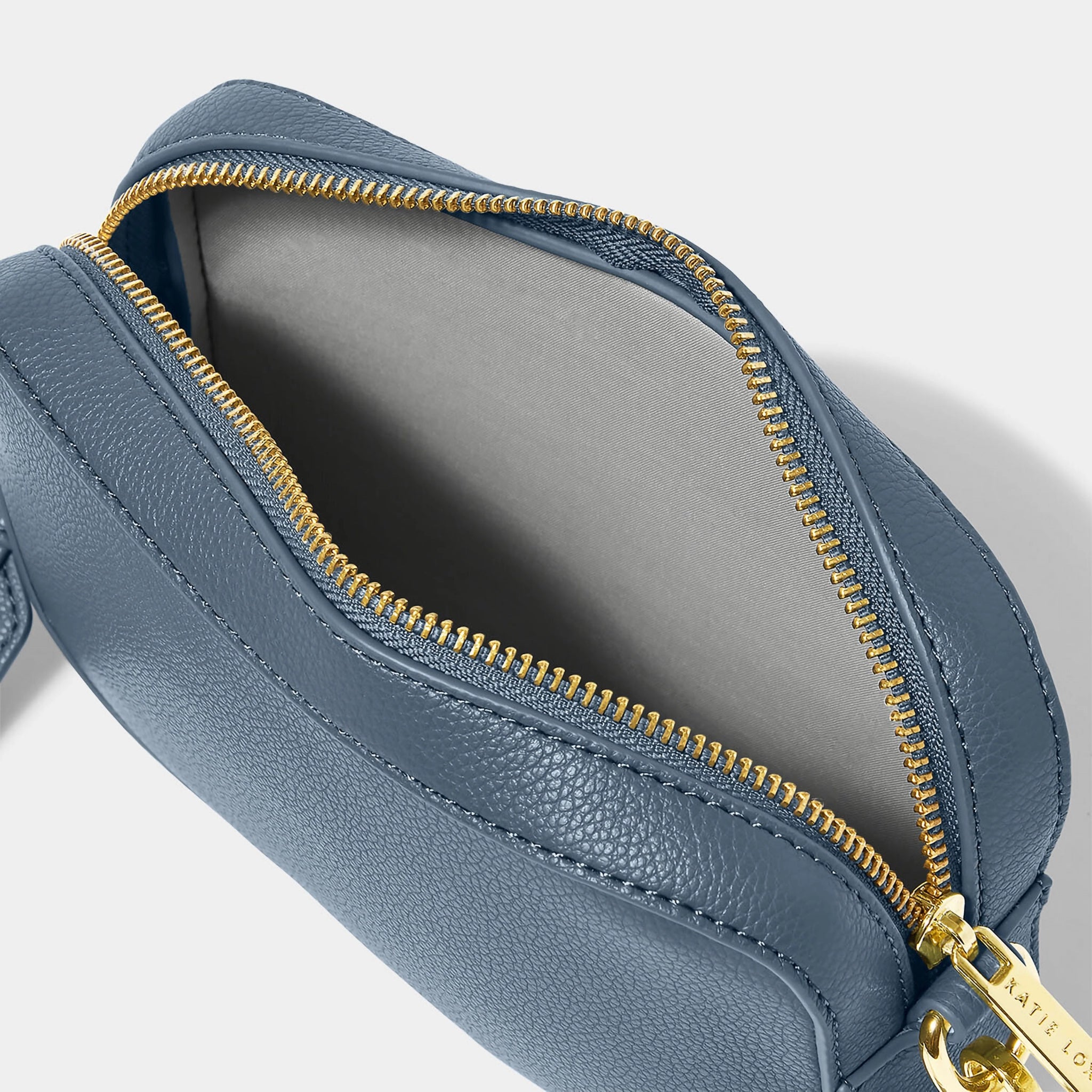 A navy blue crossbody bag in a simple box shape with adjustable canvas strap and gold hardware open