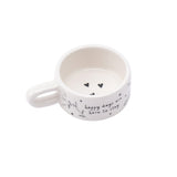 White mug shaped ceramic tealight holder with handle and heart pattern, with the phrase 'Happy days are here to stay'