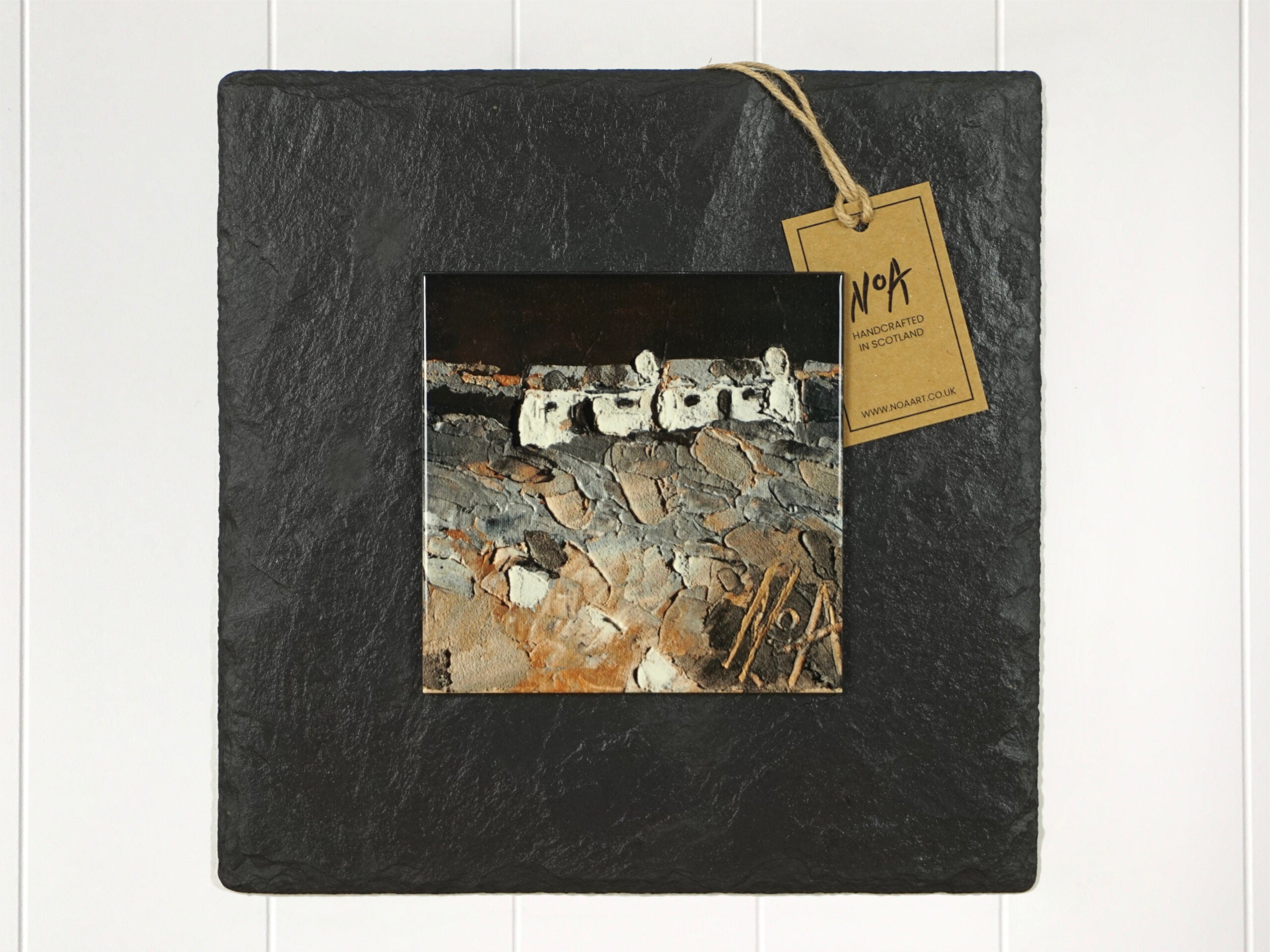 Wall art of two small white cottages with a night sky in natural and grey done in an abstract style onto a square ceramic tile mounted on square slate